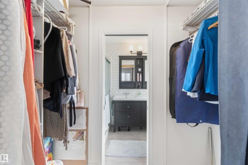 The property features a closet with wire shelving and a hanging rod, leading to a bathroom with a dark wood vanity and a white vessel sink - 4023 86 Street Nw, Edmonton, AB - Indoor With Storage