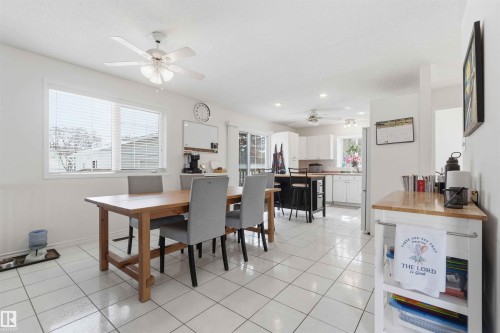 Open concept kitchen and dining area with white tile flooring and ceiling fans - 4023 86 Street Nw, Edmonton, AB - Indoor Photo Showing Dining Room
