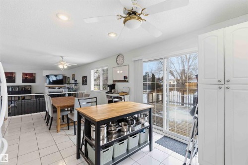 The kitchen features white cabinetry, white tiled flooring, and a large sliding glass door with views of the outdoors - 4023 86 Street Nw, Edmonton, AB - Indoor