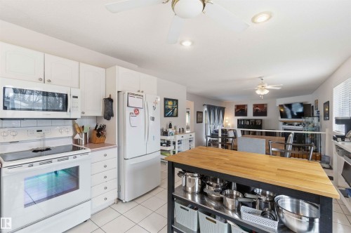The kitchen features white cabinetry, a white electric range, and a white refrigerator - 4023 86 Street Nw, Edmonton, AB - Indoor Photo Showing Kitchen