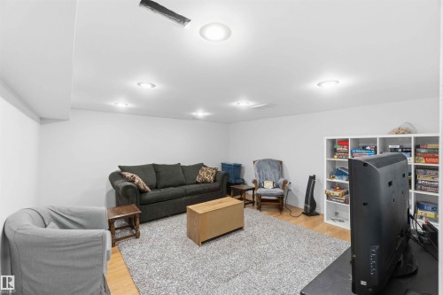This living area features light wood flooring, recessed ceiling lights, and a white built-in shelving unit - 4023 86 Street Nw, Edmonton, AB - Indoor