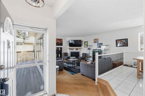 The property features a welcoming entryway with a white door and a security screen door, opening to a living area with light wood flooring - 4023 86 Street Nw, Edmonton, AB - Indoor Photo Showing Other Room