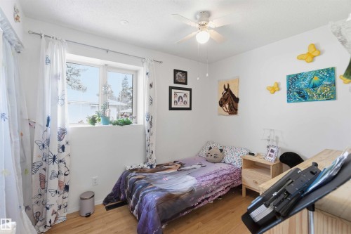 This room features light wood flooring, a window providing natural light, and a ceiling fan for comfort - 4023 86 Street Nw, Edmonton, AB - Indoor Photo Showing Bedroom