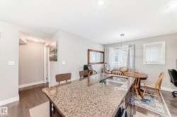 Open concept kitchen and dining area featuring a granite countertop island with a sink, hardwood flooring, and recessed lighting - 