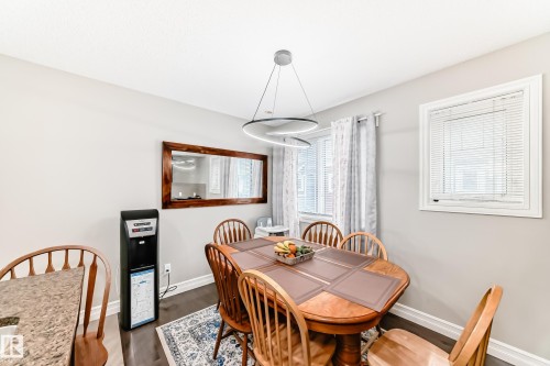 Dining area with dark wood flooring, light grey walls, and a contemporary chandelier - 138 655 Tamarack Road Nw, Edmonton, AB - Indoor Photo Showing Dining Room