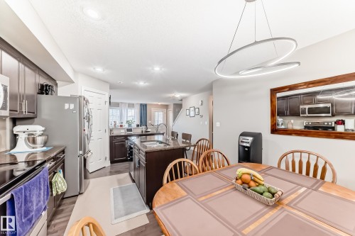 Well-appointed kitchen featuring stainless steel appliances, dark cabinetry, and a central island with a granite countertop - 138 655 Tamarack Road Nw, Edmonton, AB - Indoor