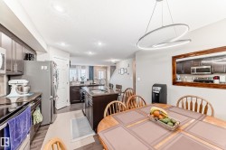Well-appointed kitchen featuring stainless steel appliances, dark cabinetry, and a central island with a granite countertop - 
