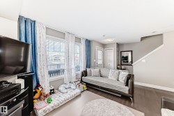 Living area featuring dark hardwood flooring, light grey walls, and windows with blinds and curtains - 
