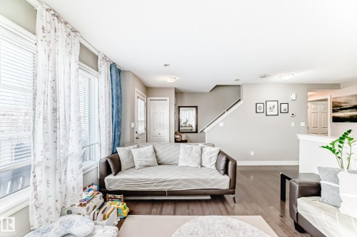 Living space featuring hardwood flooring, light-colored walls, and large windows with blinds - 138 655 Tamarack Road Nw, Edmonton, AB - Indoor Photo Showing Living Room