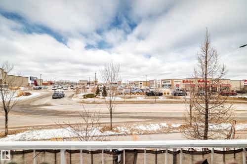 View of the surrounding area, featuring paved roads, various commercial buildings, and a parking lot with parked cars - 138 655 Tamarack Road Nw, Edmonton, AB - Outdoor With View