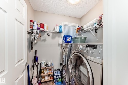 Well-appointed laundry area featuring a washer and dryer, wire shelving for storage, and a light-colored door - 138 655 Tamarack Road Nw, Edmonton, AB - Indoor Photo Showing Laundry Room