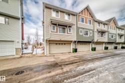 The property presents a modern exterior with siding in varying shades of beige and green, complemented by white window frames - 