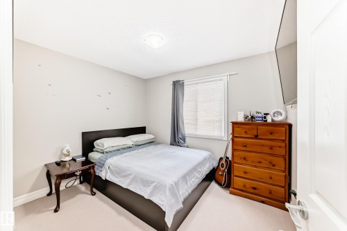 This room features light-colored carpeting, a window with blinds and drapes, and a ceiling light fixture - 138 655 Tamarack Road Nw, Edmonton, AB - Indoor Photo Showing Bedroom