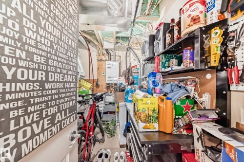 This utility room features exposed overhead pipes and a wall-mounted water heater - 138 655 Tamarack Road Nw, Edmonton, AB - Indoor Photo Showing Other Room