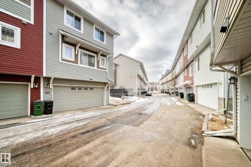 This property features a two-car garage with an overhead door, and an exterior finished with horizontal siding in shades of grey and red - 138 655 Tamarack Road Nw, Edmonton, AB - Outdoor