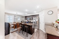 The kitchen features dark wood cabinetry, stainless steel appliances, and a central island with a granite countertop - 