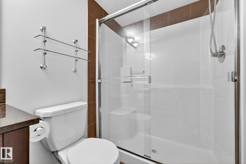 Bathroom featuring a glass-enclosed shower with a handheld showerhead and a toilet with an adjacent vanity - 301 1070 Mcconachie Boulevard, Edmonton, AB - Indoor Photo Showing Bathroom