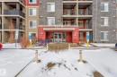 The property features a red accent entrance with the building number 1070 prominently displayed - 301 1070 Mcconachie Boulevard, Edmonton, AB  - Outdoor With Balcony With Facade 