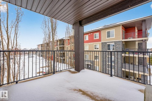 The property features a balcony with a black metal railing, providing views of the surrounding buildings and snow-covered ground - 301 1070 Mcconachie Boulevard, Edmonton, AB - Outdoor With Balcony With Exterior