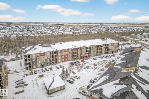 Aerial view of the property and surrounding neighborhood, featuring a multi-story building with balconies, a paved parking lot, and snow-covered grounds - 301 1070 Mcconachie Boulevard, Edmonton, AB - Outdoor With View
