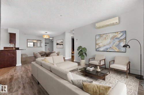 Open concept living area featuring wood-look flooring, light-colored walls, and a visible cooling unit - 301 1070 Mcconachie Boulevard, Edmonton, AB - Indoor Photo Showing Living Room