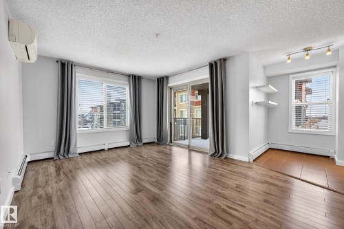 Living area featuring wide plank flooring, a window with blinds, and a sliding glass door leading to a balcony - 301 1070 Mcconachie Boulevard, Edmonton, AB - Indoor