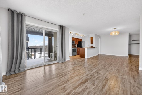 The property features hardwood style flooring, an open concept layout, and a private balcony with scenic views - 301 1070 Mcconachie Boulevard, Edmonton, AB - Indoor Photo Showing Living Room