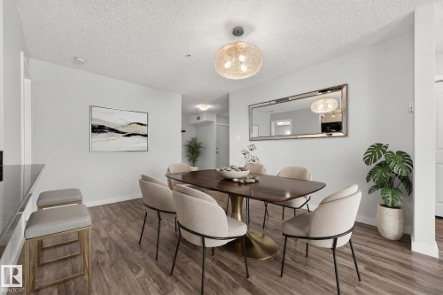 Dining area featuring wood flooring, a decorative light fixture, and a large wall mirror - 301 1070 Mcconachie Boulevard, Edmonton, AB - Indoor Photo Showing Dining Room