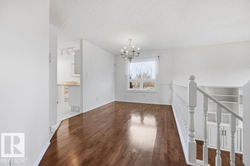 The living area features hardwood floors and a chandelier, with a window providing natural light - 3772 30 Street, Edmonton, AB - Indoor Photo Showing Other Room