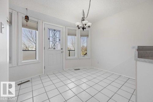 This bright space features white tile flooring, white walls, and abundant natural light from multiple windows - 3772 30 Street, Edmonton, AB - Indoor Photo Showing Other Room