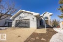 The property features a concrete driveway leading to a dark garage door, a front entrance with an arched trellis, and a large arched window - 3772 30 Street, Edmonton, AB  - Outdoor 