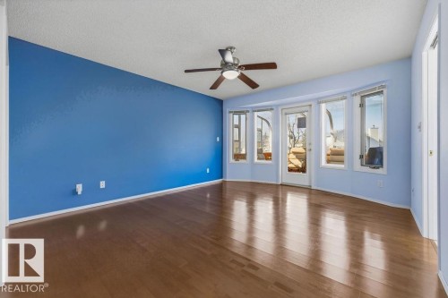 This room features polished hardwood flooring, a ceiling fan, and a wall of windows, including a glass-paneled door - 3772 30 Street, Edmonton, AB - Indoor Photo Showing Other Room