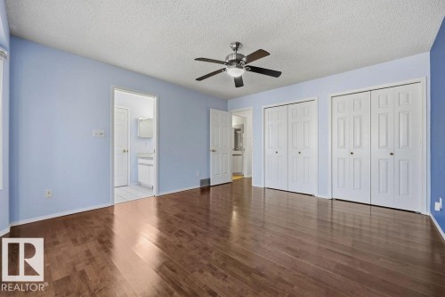 This room features rich hardwood flooring, a ceiling fan with integrated lighting, and two sets of white bifold closet doors - 3772 30 Street, Edmonton, AB - Indoor Photo Showing Other Room