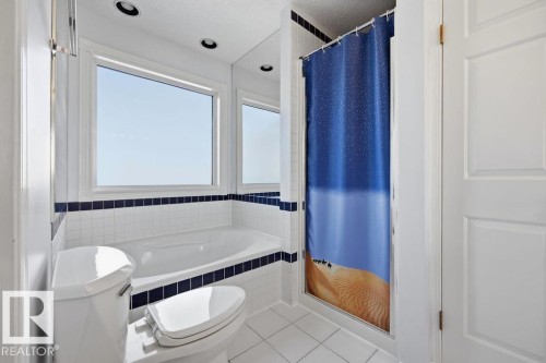 The bathroom features a built-in bathtub with tiled surround, a toilet, a shower stall with a shower curtain, and a window providing natural light - 3772 30 Street, Edmonton, AB - Indoor Photo Showing Bathroom