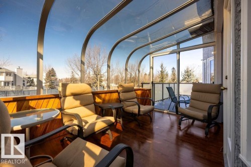 This bright sunroom features a curved glass roof and walls, rich wood flooring, and wood paneling along the lower wall situated off of the Primary Bedroom. - 3772 30 Street, Edmonton, AB - Outdoor With Exterior
