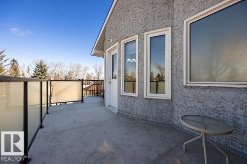 Spacious balcony featuring a glass panel railing, a white exterior door, and multiple windows providing natural light - 3772 30 Street, Edmonton, AB - Outdoor With Exterior