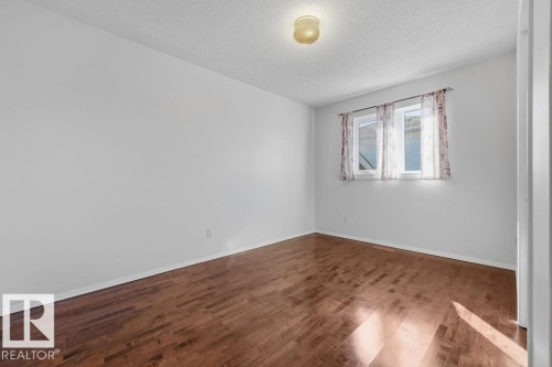 Room featuring wood flooring, neutral colored walls, a window with curtains, and an overhead light fixture - 3772 30 Street, Edmonton, AB - Indoor Photo Showing Other Room