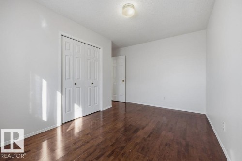 This room features rich hardwood flooring, a white bi-fold closet, and a white ceiling with a flush-mount light fixture - 3772 30 Street, Edmonton, AB - Indoor Photo Showing Other Room