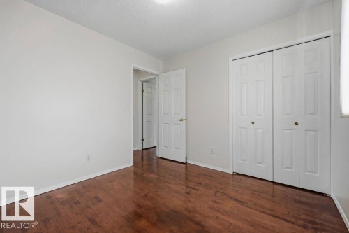 This room features rich hardwood flooring, light-colored walls, and a white bi-fold closet - 3772 30 Street, Edmonton, AB - Indoor Photo Showing Other Room