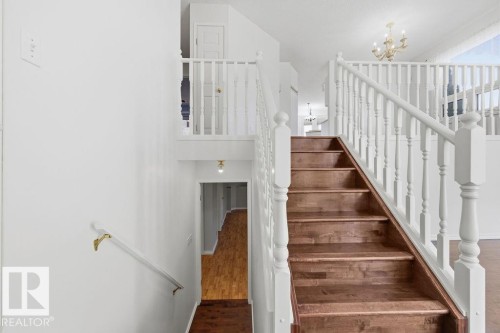 This property features a staircase with wooden treads and white railings, a white wall, and a light fixture visible overhead - 3772 30 Street, Edmonton, AB - Indoor Photo Showing Other Room