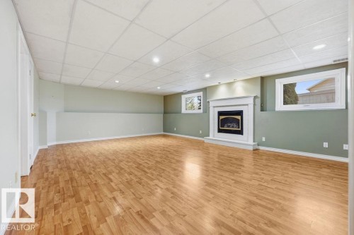 Spacious family room situated in the lower level. featuring light wood flooring, a fireplace with a white mantel, and recessed lighting - 3772 30 Street, Edmonton, AB - Indoor With Fireplace