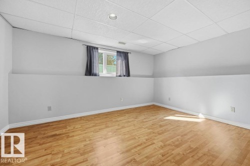 This room features light wood flooring, a window with dark drapes, and a white drop ceiling with recessed lighting - 3772 30 Street, Edmonton, AB - Indoor Photo Showing Other Room