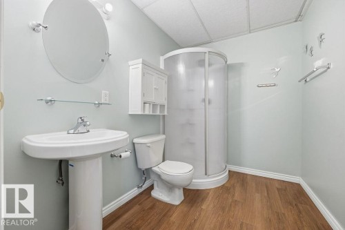 A bathroom featuring a pedestal sink, a toilet, a shower stall, and wood-look flooring - 3772 30 Street, Edmonton, AB - Indoor Photo Showing Bathroom