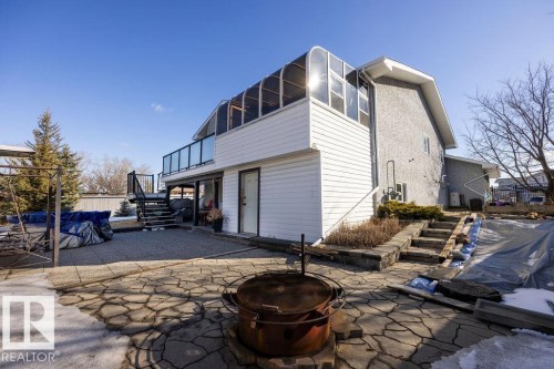 The property features a multi-level patio with flagstone paving and an upper deck with glass railings - 3772 30 Street, Edmonton, AB - Outdoor With Exterior