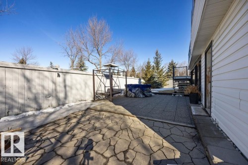 The property features a paved patio area with a distinct irregular stone pattern, a white sided exterior, and a porch with dark railings and steps - 3772 30 Street, Edmonton, AB - Outdoor