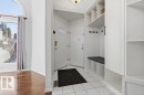 Entryway featuring white tile flooring, a built-in storage unit with shelving and hooks, and a bench with a cushion - 3772 30 Street, Edmonton, AB  - Indoor Photo Showing Other Room 