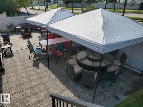 Expansive paved patio area featuring a privacy fence and two white canopy structures - 3772 30 Street, Edmonton, AB - Outdoor With Deck Patio Veranda