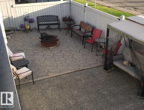 The property features a paved patio area, complete with a fire pit, and is enclosed by a white fence - 3772 30 Street, Edmonton, AB - Outdoor With Deck Patio Veranda