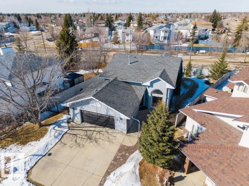 The property features an attached garage with a paved driveway, a gabled roof, and a mature evergreen tree in the front yard - 3772 30 Street, Edmonton, AB - Outdoor