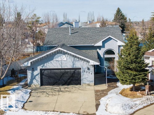 The property features a stucco exterior, an attached garage with a black door, and a paved driveway - 3772 30 Street, Edmonton, AB - Outdoor
